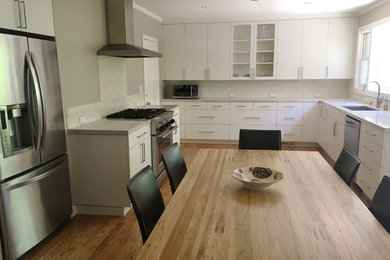 Example of a mid-sized minimalist dark wood floor and brown floor eat-in kitchen design in San Francisco with a single-bowl sink, flat-panel cabinets, white cabinets, marble countertops, white backsplash, glass tile backsplash, stainless steel appliances, no island and gray countertops