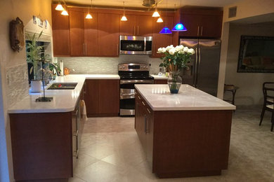 Example of a trendy l-shaped beige floor and ceramic tile open concept kitchen design in Miami with a double-bowl sink, flat-panel cabinets, medium tone wood cabinets, quartzite countertops, gray backsplash, glass tile backsplash, stainless steel appliances and an island