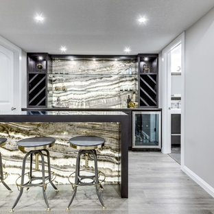 カルガリーの中サイズのコンテンポラリースタイルのおしゃれな着席型バー (シンクなし、フラットパネル扉のキャビネット、茶色いキャビネット、クオーツストーンカウンター、マルチカラーのキッチンパネル、石スラブのキッチンパネル、クッションフロア、グレーの床、茶色いキッチンカウンター) の写真
