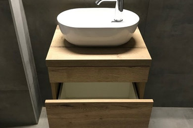 Kleine Moderne Gästetoilette mit flächenbündigen Schrankfronten, hellbraunen Holzschränken, grauen Fliesen, Aufsatzwaschbecken, Waschtisch aus Holz und grauem Boden in Köln