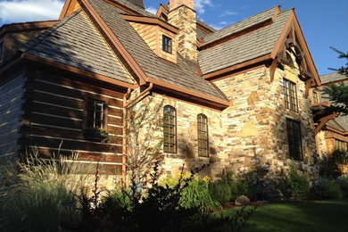 Large rustic brown three-story stone gable roof idea in Other