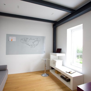 Design ideas for a small modern study in Dusseldorf with white walls, light hardwood flooring, a freestanding desk and yellow floors.