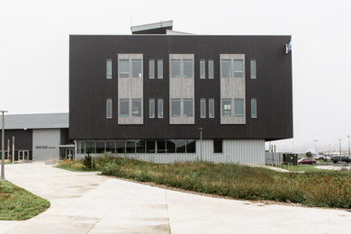 Foto della facciata di una casa ampia nera industriale a quattro piani con rivestimento in legno