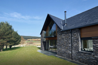Inspiration for a large contemporary two-storey grey house exterior with stone veneer, a gable roof and a tile roof.