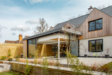 Modelo de fachada de casa blanca y gris actual grande de dos plantas con revestimiento de madera, tejado a dos aguas, tejado de teja de barro y panel y listón