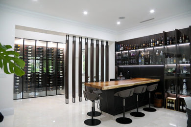 Example of a trendy l-shaped white floor wet bar design in Miami with a drop-in sink, glass-front cabinets, wood countertops and black backsplash