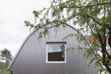 Foto della villa grigia contemporanea a un piano di medie dimensioni con rivestimento in legno, tetto grigio, pannelli sovrapposti e copertura in metallo o lamiera