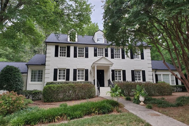 Example of a classic white exterior home design in Raleigh with a black roof