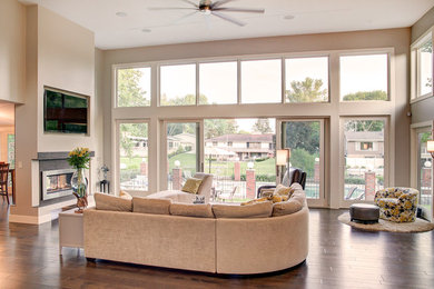 Large minimalist open concept medium tone wood floor and brown floor living room photo in Other with a two-sided fireplace, a wood fireplace surround, a media wall and gray walls