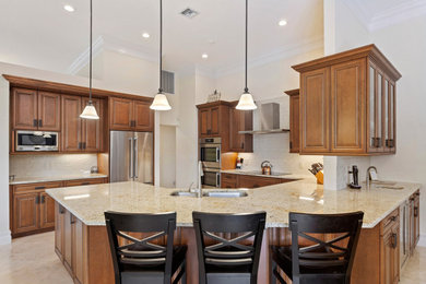 Large transitional u-shaped marble floor and beige floor open concept kitchen photo in Miami with an undermount sink, raised-panel cabinets, medium tone wood cabinets, granite countertops, beige backsplash, subway tile backsplash, stainless steel appliances, a peninsula and beige countertops