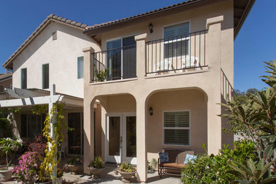 Mid-sized mediterranean beige two-story stucco house exterior idea in San Diego with a hip roof and a tile roof