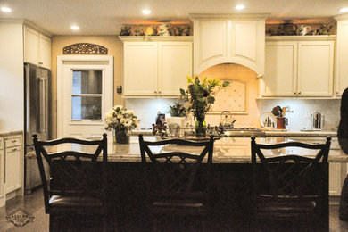 Inspiration for a mid-sized transitional single-wall eat-in kitchen remodel in Los Angeles with an undermount sink, recessed-panel cabinets, white cabinets, granite countertops, beige backsplash, ceramic backsplash, stainless steel appliances and an island