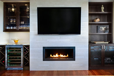 Photo of a large contemporary living room in Denver with a home bar, beige walls, medium hardwood floors, a ribbon fireplace, a stone fireplace surround and a wall-mounted tv.