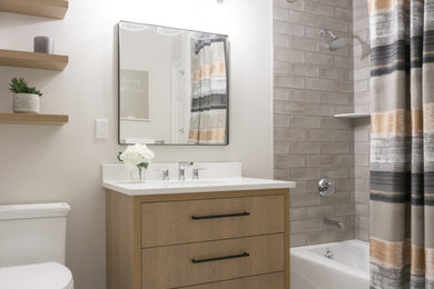 Example of a mid-sized trendy gray tile and ceramic tile porcelain tile, white floor and single-sink bathroom design in Other with flat-panel cabinets, medium tone wood cabinets, a one-piece toilet, gray walls, an undermount sink, quartzite countertops, white countertops and a freestanding vanity