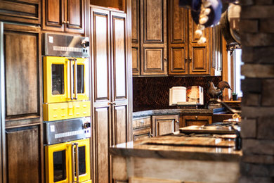 Inspiration for a large rustic l-shaped brick floor eat-in kitchen remodel in Kansas City with raised-panel cabinets, granite countertops, metallic backsplash, metal backsplash, paneled appliances and an island