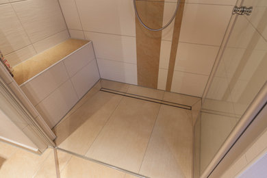 Photo of a traditional bathroom in Other with a drop-in tub, a curbless shower, a wall-mount toilet, white tile, ceramic tile, beige walls, ceramic floors, a drop-in sink, solid surface benchtops, beige floor and a hinged shower door.