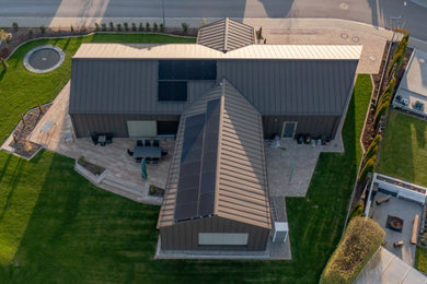 Esempio della facciata di una casa marrone industriale a un piano con rivestimento in metallo, tetto a capanna, copertura in metallo o lamiera e tetto marrone