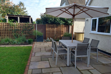 Design ideas for a large midcentury back patio in Surrey with a bbq area and natural stone paving.