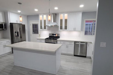Inspiration for a large modern u-shaped laminate floor, gray floor and tray ceiling open concept kitchen remodel in Los Angeles with a drop-in sink, beaded inset cabinets, white cabinets, quartz countertops, white backsplash, cement tile backsplash, stainless steel appliances, an island and white countertops