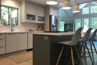 Example of a mid-sized trendy l-shaped laminate floor and beige floor open concept kitchen design in Other with an undermount sink, flat-panel cabinets, gray cabinets, quartz countertops, white backsplash, porcelain backsplash, stainless steel appliances, an island and white countertops