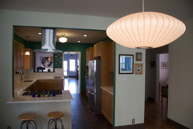 Example of a mid-sized asian l-shaped slate floor and brown floor eat-in kitchen design in Atlanta with an undermount sink, shaker cabinets, light wood cabinets, laminate countertops, white backsplash, ceramic backsplash, stainless steel appliances and a peninsula