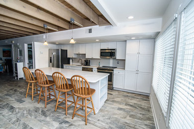 Example of a mid-sized classic single-wall porcelain tile and multicolored floor eat-in kitchen design in Other with an undermount sink, recessed-panel cabinets, white cabinets, marble countertops, stainless steel appliances, an island and white countertops