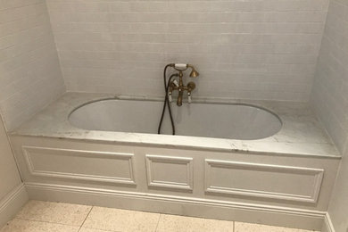 Cette photo montre une petite salle d'eau rétro avec des portes de placard grises, une baignoire encastrée, un carrelage gris, un carrelage métro et un sol en terrazzo.