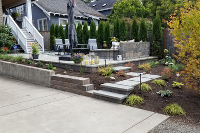 Photo of a medium sized contemporary back full sun garden for summer in Seattle with a fire feature, natural stone paving and a wood fence.