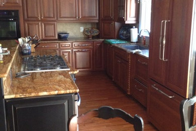Inspiration for a mid-sized timeless l-shaped medium tone wood floor and brown floor eat-in kitchen remodel in Other with an undermount sink, raised-panel cabinets, medium tone wood cabinets, granite countertops, paneled appliances and an island