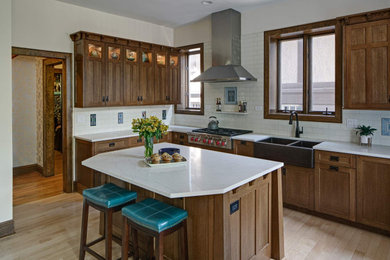 Eat-in kitchen - large craftsman l-shaped light wood floor and beige floor eat-in kitchen idea in Chicago with a farmhouse sink, recessed-panel cabinets, medium tone wood cabinets, quartz countertops, white backsplash, ceramic backsplash, paneled appliances, an island and white countertops