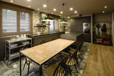 This is an example of a large industrial l-shaped eat-in kitchen in Barcelona with flat-panel cabinets, grey cabinets, multi-coloured splashback, ceramic splashback, stainless steel appliances, ceramic floors and with island.