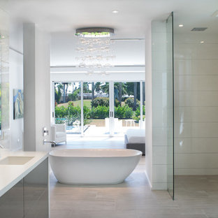 Esempio di una grande stanza da bagno padronale moderna con ante lisce, ante grigie, vasca freestanding, WC monopezzo, pareti bianche, lavabo integrato, doccia aperta, piastrelle bianche, lastra di vetro, pavimento in laminato, top in superficie solida, pavimento beige e doccia aperta