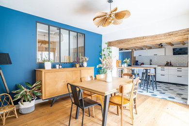Idées déco pour une salle à manger campagne de taille moyenne avec un mur bleu, parquet clair, un sol marron, poutres apparentes et une cheminée standard.