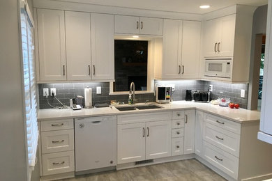 Example of a mid-sized transitional vinyl floor and gray floor kitchen design in Minneapolis with an undermount sink, recessed-panel cabinets, white cabinets, quartz countertops, gray backsplash, subway tile backsplash, white appliances and no island