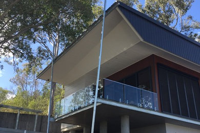 This is an example of an expansive modern side yard deck in Brisbane with a roof extension.