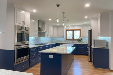 Inspiration for a mid-sized modern u-shaped light wood floor and brown floor eat-in kitchen remodel in Chicago with an undermount sink, raised-panel cabinets, blue cabinets, white backsplash, glass tile backsplash, stainless steel appliances, an island and white countertops