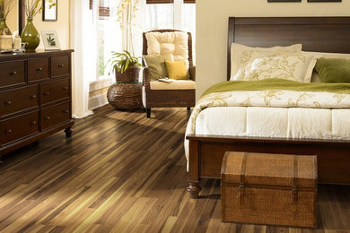Ejemplo de dormitorio principal clásico de tamaño medio con suelo laminado, suelo marrón y paredes beige