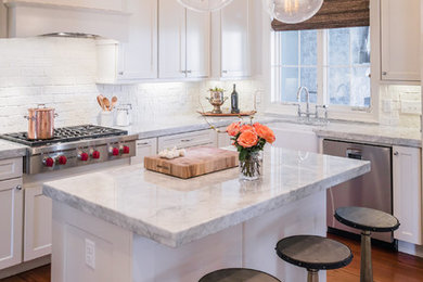 Inspiration for a transitional l-shaped kitchen in Other with a farmhouse sink, shaker cabinets, white cabinets, white splashback, brick splashback, stainless steel appliances, dark hardwood floors, with island, marble benchtops, brown floor and grey benchtop.