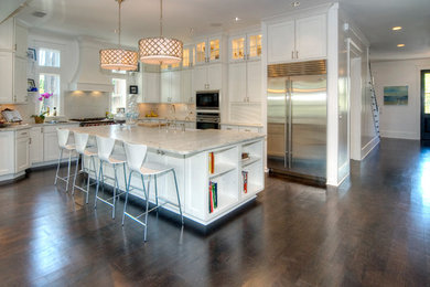 Example of a large transitional l-shaped dark wood floor and brown floor open concept kitchen design in Miami with a farmhouse sink, shaker cabinets, white cabinets, marble countertops, white backsplash, ceramic backsplash, stainless steel appliances and an island