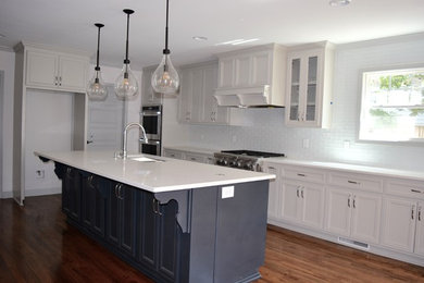 Inspiration for a mid-sized transitional single-wall dark wood floor open concept kitchen remodel in Atlanta with an undermount sink, beaded inset cabinets, gray cabinets, quartz countertops, white backsplash, subway tile backsplash, stainless steel appliances and an island