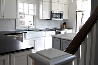 Inspiration for a transitional medium tone wood floor eat-in kitchen remodel in Omaha with a farmhouse sink, raised-panel cabinets, white cabinets, granite countertops, white backsplash, subway tile backsplash, stainless steel appliances and an island