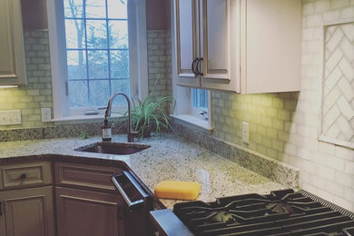 Example of a large transitional l-shaped kitchen design in Boston with an undermount sink, raised-panel cabinets, gray cabinets, granite countertops, gray backsplash, subway tile backsplash, stainless steel appliances and multicolored countertops