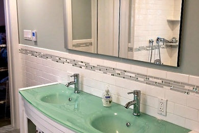 Design ideas for a mid-sized transitional 3/4 bathroom in Chicago with white cabinets, a shower/bathtub combo, blue tile, gray tile, white tile, subway tile, an integrated sink, glass benchtops, grey floor, furniture-like cabinets, a drop-in tub, white walls and turquoise benchtops.