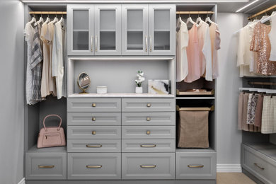 Large trendy women's walk-in closet photo in Denver with raised-panel cabinets and gray cabinets