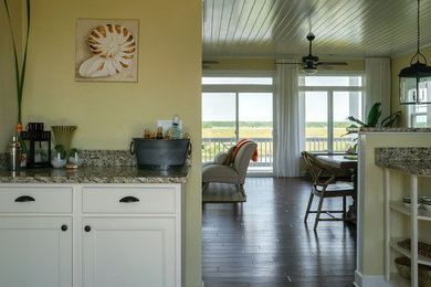 Home bar - small coastal single-wall medium tone wood floor home bar idea in Atlanta with recessed-panel cabinets, beige cabinets and granite countertops