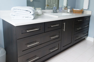Transitional porcelain tile and white floor bathroom photo in Toronto with shaker cabinets, dark wood cabinets, blue walls, a drop-in sink and solid surface countertops