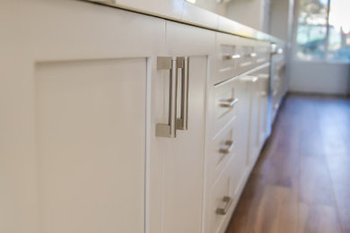 Inspiration for a contemporary kitchen remodel in Other with shaker cabinets, white cabinets, quartz countertops, white backsplash, quartz backsplash, stainless steel appliances and an island