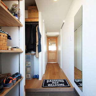 他の地域の片開きドアインダストリアルスタイルのおしゃれな玄関ホール (白い壁、木目調のドア、グレーの床) の写真