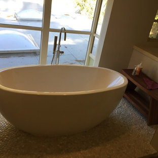 Immagine di una grande stanza da bagno padronale moderna con ante lisce, ante in legno scuro, vasca freestanding, doccia ad angolo, WC monopezzo, piastrelle beige, piastrelle in gres porcellanato, pareti beige, pavimento con piastrelle di ciottoli, lavabo sottopiano, top in rame e pavimento beige