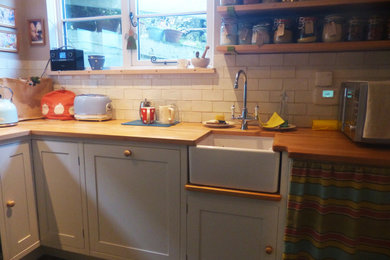 Small classic l-shaped enclosed kitchen in Cornwall with a belfast sink, shaker cabinets, wood worktops, stainless steel appliances, slate flooring, no island, grey floors and brown worktops.
